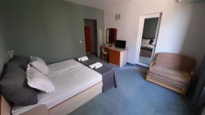 a small bedroom with a bed and a chair at Family Hotel Saga in Ravda
