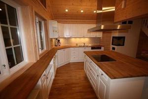 a large kitchen with white cabinets and wooden floors at Flott utleiehytte på Gautefall in Treungen