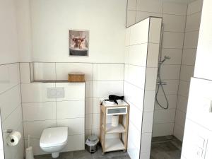 ein weißes Badezimmer mit Toilette und Dusche in der Unterkunft Ferienwohnung "Calypso" Papenburg Ebenerdig Terrasse Einbauküche Neubau 84 qm Free Wifi 2 Schlafzimmer in Papenburg + 40 Fotos