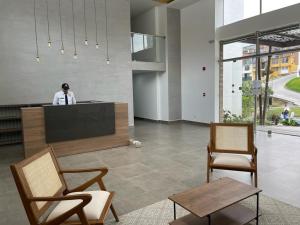 a person standing at a counter in a room with chairs at Apartamento Exclusivo Manizales in Manizales