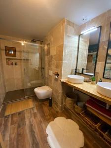a bathroom with two sinks and a shower and a toilet at Jolie maison de campagne à la ville chez TINAT in Tregueux