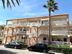 Dos coches aparcados delante de un gran edificio. en Apartamento en La Manga, Vistas mar, Wifi, AA, en La Manga del Mar Menor