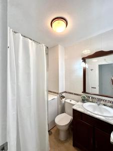 Un baño con una cortina de ducha blanca y un inodoro. en Apartamento en La Manga, Vistas mar, Wifi, AA, en La Manga del Mar Menor