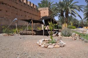un giardino con tenda e rocce di fronte a un edificio di BIVOUAC Sous Les Palmiers Bleus a Ouijjane