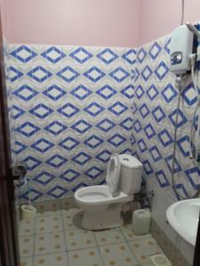 a bathroom with a toilet and a blue and white tiled wall at Pearl Motel Wing in Mukono