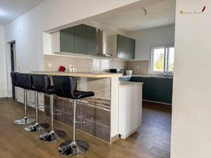 a kitchen with green cabinets and black bar stools at Villa Esthera Appartement Etage in Antsiranana