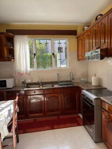 a kitchen with wooden cabinets and a sink and a window at Casa Gonçalves in São Vicente +3 photos