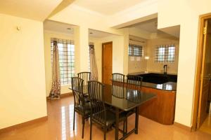 a dining room with a table and chairs and a kitchen at Lazo Silver Lake , Ooty in Ooty