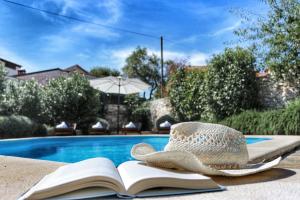 a hat sitting on a book next to a swimming pool at Villa Lucija in Rovinjsko Selo