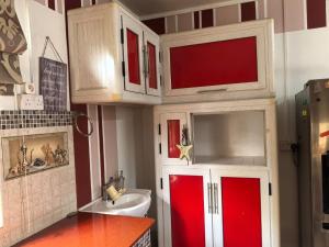 a small kitchen with red and white cabinets and a sink at Soothing home in Brisée Verdière +44 photos