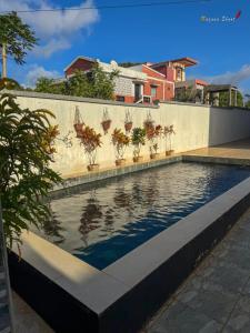 a swimming pool with plants on a wall at Villa Esthera RDC in Antsiranana