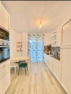 a kitchen with white cabinets and a table with a green chair at Casa Vacanze Cimo Marine Style in Civitanova Marche