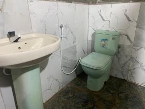 a bathroom with a green toilet and a sink at Jaffna City Rest in Jaffna