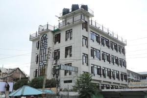 un edificio blanco alto con un reloj en él en Hotel New Mamta, en Srinagar
