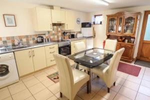 une cuisine avec une table en verre et des chaises blanches dans l'établissement Clares Cosy Cottage, à Louth