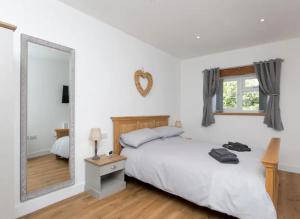 ein Schlafzimmer mit einem weißen Bett und einem großen Spiegel in der Unterkunft Adorable 1 bedroom Country Cottage in Bodewryd