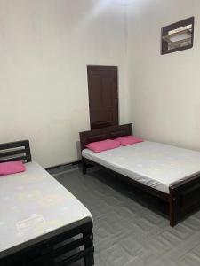 two beds in a room with pink sheets at Jaffna City Rest in Jaffna