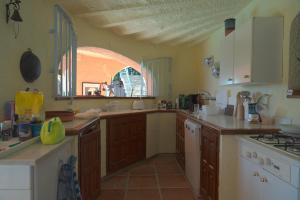 a kitchen with wooden cabinets and an arched window at Casa Buenaventura in Calonge