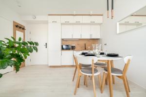 biała kuchnia z białym stołem i krzesłami w obiekcie Westin House Resort Kołobrzeg Apartament 410 w Kołobrzegu