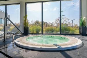 wanna z hydromasażem na środku pokoju z oknami w obiekcie Westin House Resort Kołobrzeg Apartament 410 w Kołobrzegu