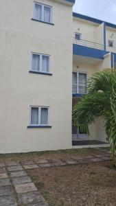 a white building with a palm tree in front of it at Jems Appartment Villa in Mare Sèche