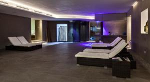 sala de estar con 2 sillas blancas e iluminación púrpura en Hotel Saccardi & Spa - Adults Only, en Caselle di Sommacampagna