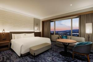 a bedroom with a bed and a table and a large window at The Westin Osaka in Osaka