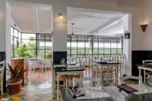 a restaurant with tables and chairs and large windows at Hôtel Restaurant Les Remparts in Venasque +21 photos