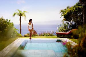 a woman is standing next to a swimming pool at The Ritz-Carlton Tenerife, Abama in Guía de Isora