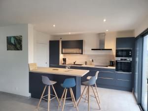 a kitchen with blue cabinets and a table and stools at Villa l'estran récente vue mer Plounéour-Brignogan-plages in Plounéour-Trez