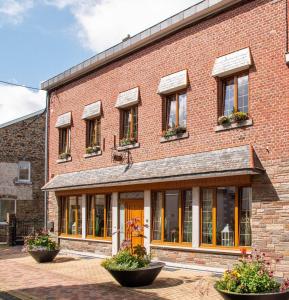 a brick building with windows and plants in front of it at Gite les bons amis in Plombières