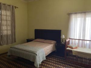 a bedroom with a bed and a crib and a window at Casa con piscina para 8 personas in Mercedes +20 photos