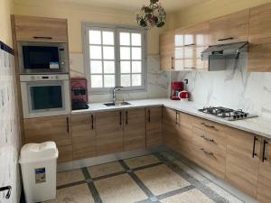 a kitchen with wooden cabinets and a sink and a stove at Villa appartement jardin et piscine in Meknès
