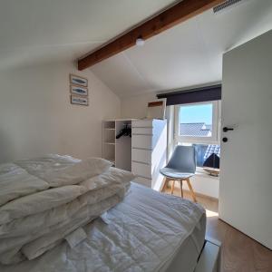 Un dormitorio con una cama y una silla y una ventana. en Maison Maritime, en Middelkerke