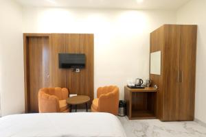 a hotel room with a bed and a table and chairs at Hotel Shrinath Palace in Mathura