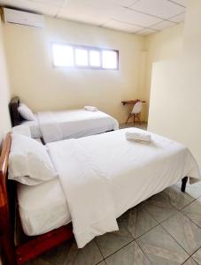 two twin beds in a room with a window at Casa Playa Los Marinos in Puerto Baquerizo Moreno