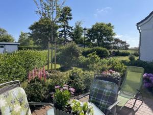 a patio with two chairs and a garden with flowers at Deichhof Whg 23 in Dunsum