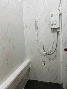 a white tiled bathroom with a hair dryer on the wall at Megun 10 Duplex in Bangkok +7 photos