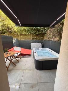 a hot tub sitting on a patio with a table at Petit studio et son spa abrité in Nancy