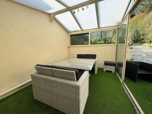 ein Wintergarten mit Tisch und Stühlen auf grünem Boden in der Unterkunft Le Cocon de Karine - maison Boulogne Sur Mer in Saint-Martin-Boulogne