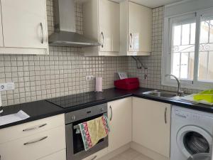 a kitchen with white cabinets and a sink and a dishwasher at Lovely 2 bedroom apartment on El Divino, Los Alcazares in Los Alcázares