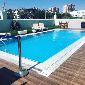 a large blue swimming pool with chairs on a roof at akdenız suıtes in Altınkum