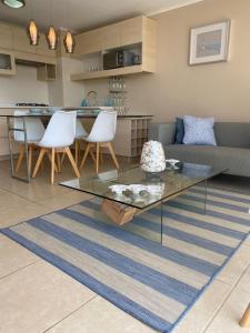 a living room with a glass table and white chairs at Resort Laguna Bahía, Océano Piso 12 Algarrobo in Algarrobo