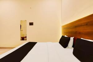 a bedroom with a white bed and a wooden headboard at Super Hotel O Sr Grand in Gorakhpur