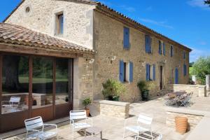 a stone house with white chairs and a patio at 4 stars farmhouse, heated pool, view, 15 people in Bonnieux