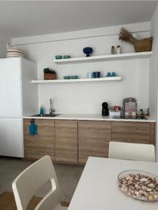 a kitchen with a white refrigerator and a table and chairs at White home Marzamemi in Marzamemi