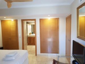a room with a bed and a tv and a mirror at Apartamento duplex en resort de golf y playa in Atamaría +20 photos