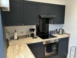 a kitchen with black cabinets and a stove top oven at The Staff Quarters in Shifnal