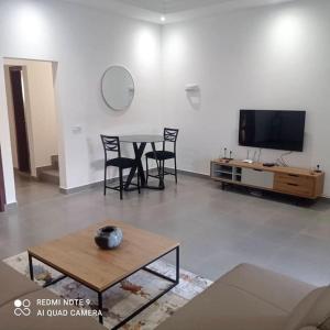 a living room with a table and chairs and a tv at La Villa Grenade in Pointe-Noire
