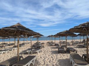a beach with chairs and umbrellas and the ocean at Paradise in Cabanas de Tavira in Cabanas de Tavira